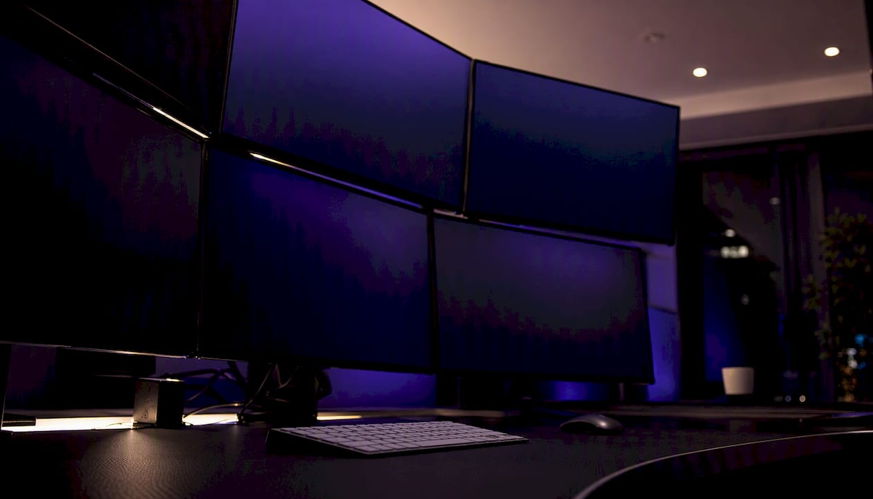 Dark trading desk with multi-monitor setup and abstract charts