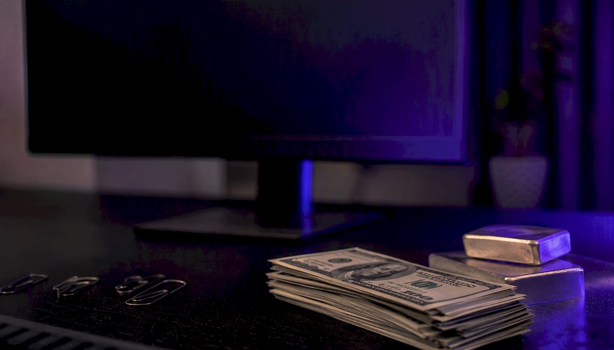 Close-up of cash and gold bars on trading desk