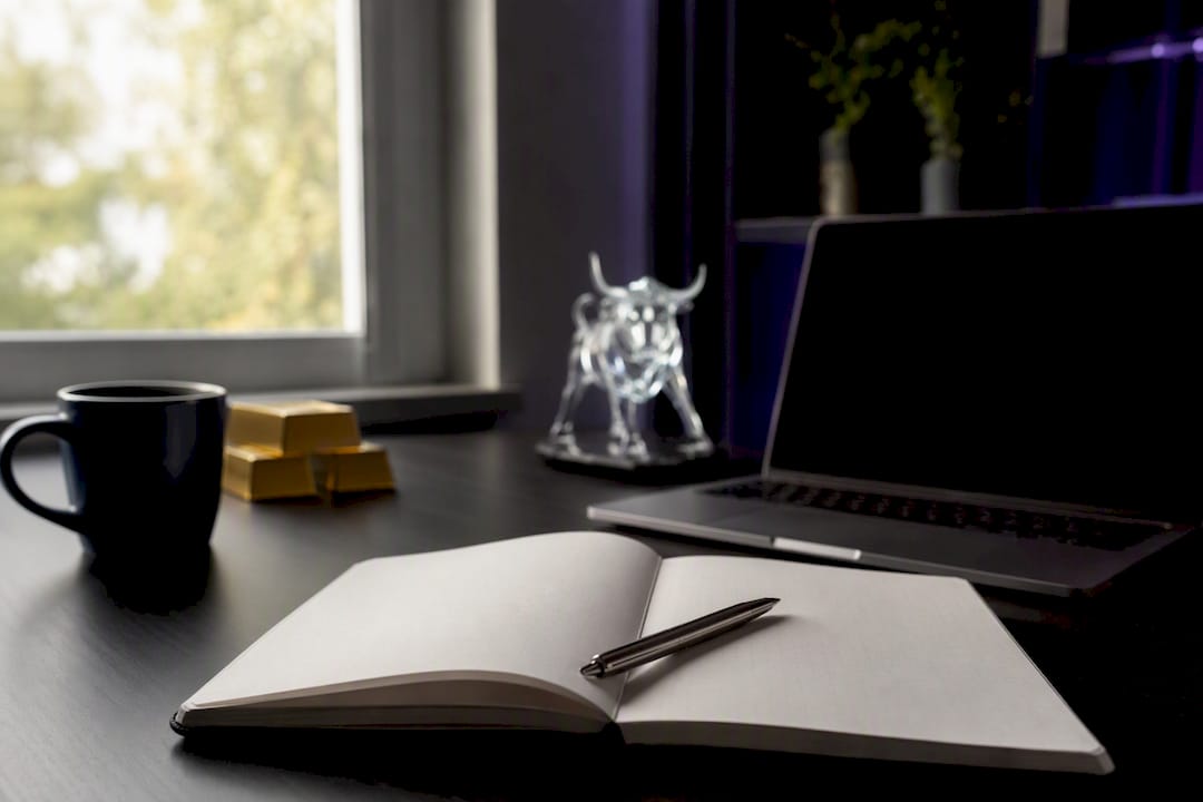Trader journal open on desk with pen and charts reflected